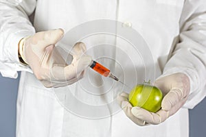 Laboratory assistant injects into a green tomato with nitrates so that they are fresh, GMOs