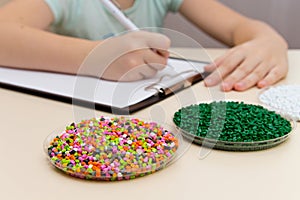 Laboratory assistant inspections plastic pellets for industry. P