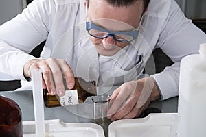 Laboratory assistant pours liquid from a bottle with sodium oxalate