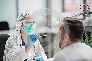 A laboratory assistant in a private clinic takes a swab from the patient's nasopharynx, a PCR test for coronavirus covid