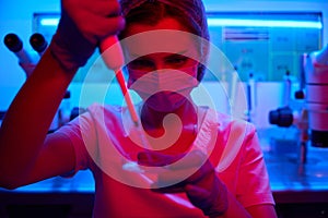 Laboratory assistant in a protective mask manipulates the biomaterial
