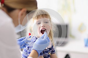 Laboratory assistant in protective suit takes swab from childs throat, procedure at home