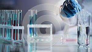 Laboratory assistant putting pipette into sterile mixture after conducting tests