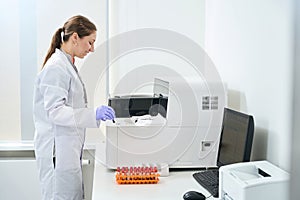 Laboratory assistant stands near a hematological analyzer in testing unit