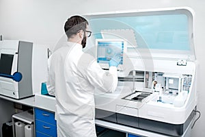 Laboratory assistant working with medical analizer machine
