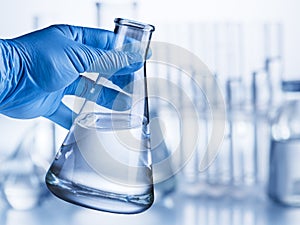 Laboratory beaker in analyst`s hand.