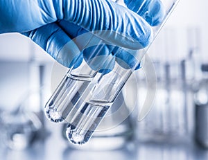 Laboratory beakers in analyst`s hand.