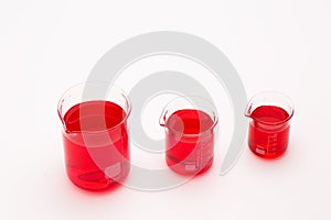 Laboratory equipment, beakers filled by red liquid on white table. Science concept.