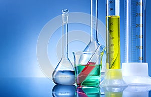 Laboratory equipment, bottles, flasks with color liquid on blue background