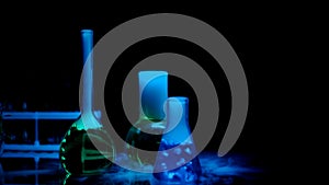 Laboratory flasks with chemical liquids emitting smoke under blue blue light