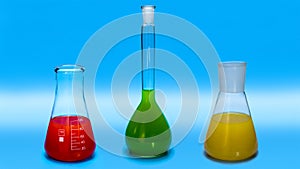 Laboratory glass chemical flasks with multi-colored liquids on a blue background. Laboratory equipment
