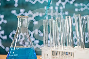 Laboratory glassware with blackboard background with various chemical formulas