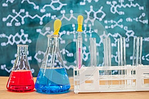 Laboratory glassware with blackboard background with various chemical formulas