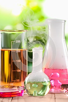 Laboratory glassware with colorful liquids on wooden table outdoors. Chemical reaction