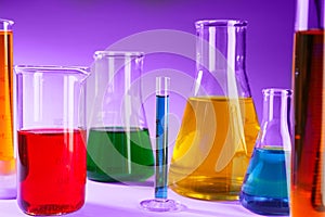 Laboratory glassware with different liquids on color background