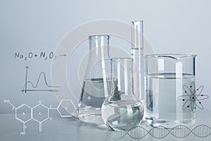 Laboratory glassware with liquids for analysis on table and chemical formulas