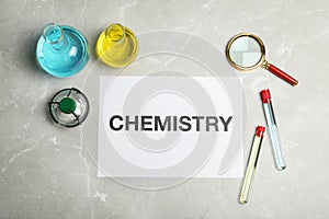 Laboratory glassware and paper with word CHEMISTRY on grey background