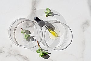 Laboratory glassware with serum and mint oil on marble background. Natural medicine, cosmetic research, bio science, organic skin