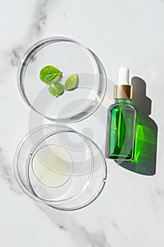 Laboratory glassware with serum and mint oil on white marble background. Natural medicine, cosmetic research, bio science, organic