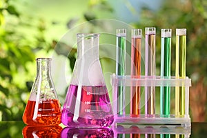 Laboratory glassware and test tubes with liquids on glass table outdoors. Chemical reaction