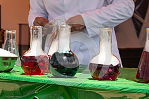 Laboratory glassware and test tubes with liquids on glass table outdoors. Chemical reaction