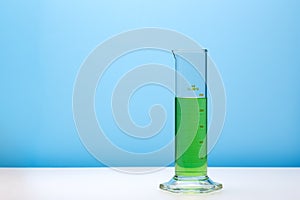 Laboratory graduated cylinder with green liquid. Copy space