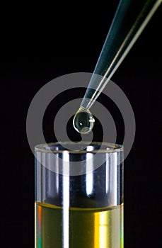 Laboratory pipette with a drop of substance over test tubes