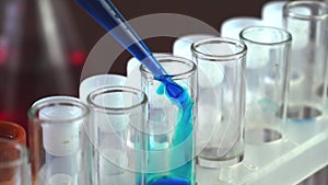 In a laboratory, a scientist with a pipette analyzes a blue liquid to extract the DNA and molecules in the test tubes. Doctor work