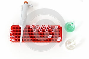 Laboratory table with flask, digital pipette and small plastic test tubes.