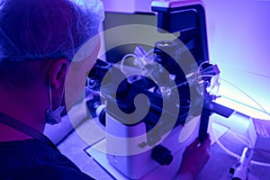 Laboratory technician is adjusting microscope with micromanipulator