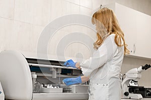 Laboratory technician test blood in automatic blood sample analyzer