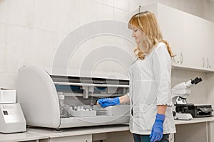 Laboratory technician test blood in automatic blood sample analyzer