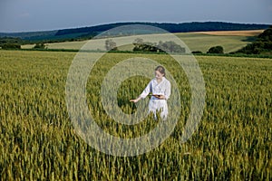 Laboratory-technician using digital tablet computer in a cultivated wheat field, application of modern technologies in