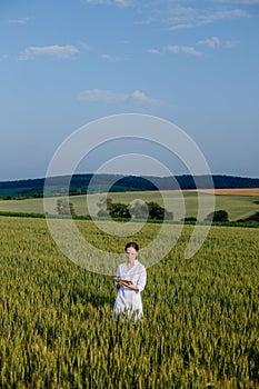 Laboratory-technician using digital tablet computer in a cultivated wheat field, application of modern technologies in