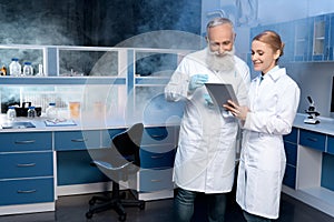 Laboratory technicians in lab coats looking at digital tablet during work in laboratory