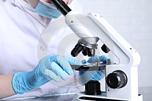 Laboratory testing. Scientist examining sample on slide under microscope indoors, closeup