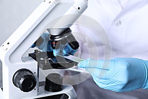 Laboratory testing. Scientist examining sample on slide under microscope indoors, closeup