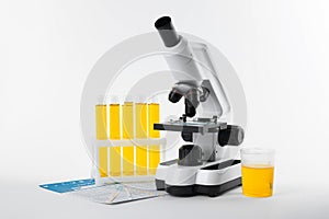 Laboratory ware with urine sample for analysis and microscope on background