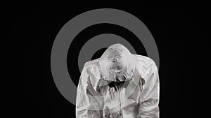 Laboratory worker in a chemical protection suit, panting, raises his head