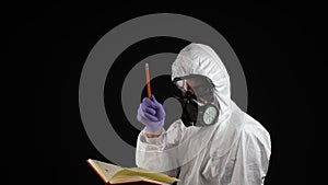 Laboratory worker in a chemical protection suit writes in a notebook with a pencil