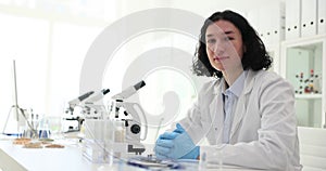 Laboratory worker with dark hair at table with microscopes