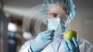 Laboratory worker injecting apple with chemicals, adding smell and juiciness