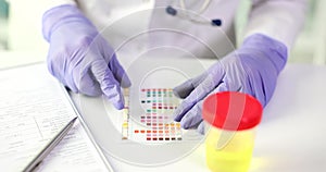 Laboratory worker matches color with test indicator paper