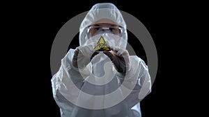 Laboratory worker in protective suit showing biological hazard symbol, weapon