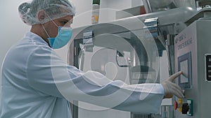 Laboratory worker pushing buttons at the machine in laboratory