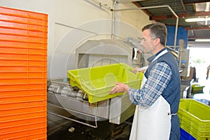 laborer cleaning plastic crates