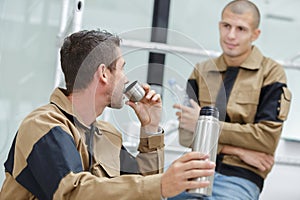 laborer drinking warm beverage from portable thermos