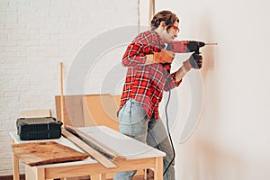 Laborer girl drilling wall with drill