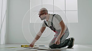 Laborer with glasses measures parquet with retractable tape