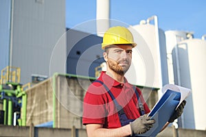 Laborer outside a factory working dressed with safety overalls e